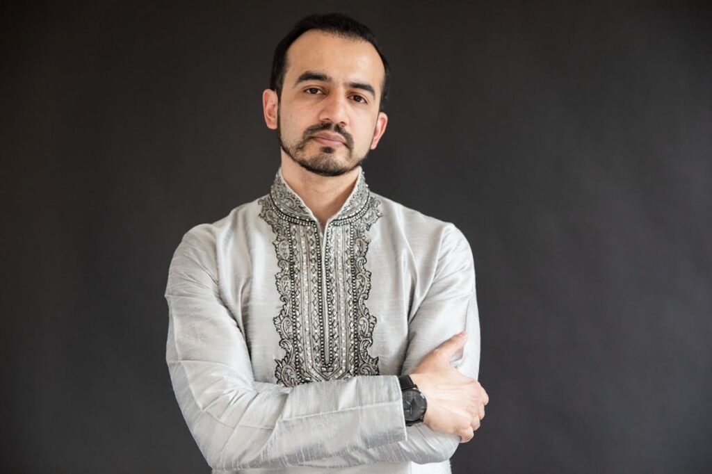 Home Studio portrait of a man wearing traditional embroidered clothes, arms crossed.